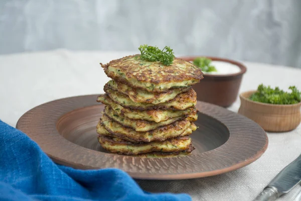 Frittelle di zucchine. Frittelle di zucchine vegetariane con erbe fresche e panna acida. Una pila di pancake. Tavolo da pranzo. Equilibrio cibo sano. Sfondo chiaro . — Foto Stock