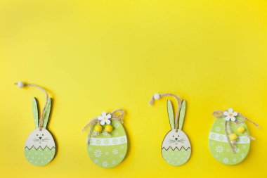 Paskalya arkaplanı, düz yatak. Paskalya süsleri, dekorasyon. Paskalya tavşanı ve parlak sarı arka plandaki bir ağaçtan gelen paskalya yumurtaları. Uzayı kopyala Metin için yer.
