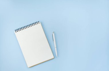 Mavi arka planda beyaz kalemli boş bir spiral defter. Modaya uygun renk ve tarz. Daire yalan söylüyordu. Uzayı kopyala Bir blogcu fikri.