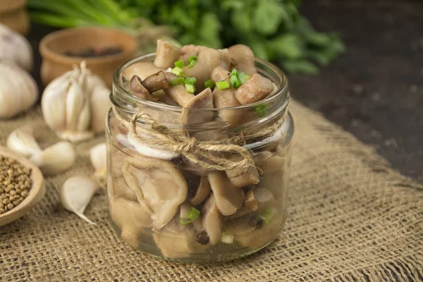 Pickled mushrooms in a glass jar. Mushrooms with herbs and spices. House food. Pickled vegetables. Vegetarian food. Side view, close-up. Copy space