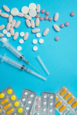 Aşı için şırınga ve mavi arka planda haplar. Tıbbi konular. İlaçlar. Virüsten kimlik tespiti. Mesaj için yer. Boşluğu kopyala.