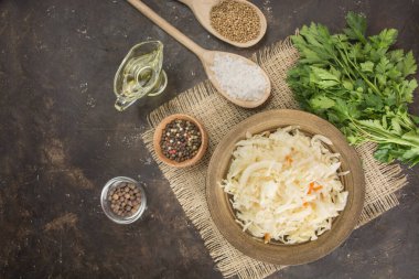 Sauerkraut with carrots in a bowl on a dark background. Fermented food. Pickled vegetables. Vegetarian, vegan food. Copy space. Side view. Table of the background menu.