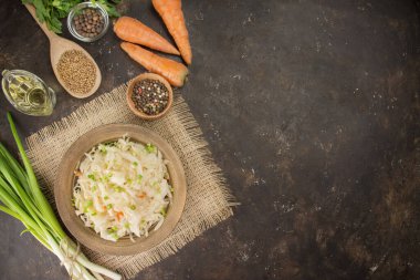 Sauerkraut with carrots in a bowl on a dark background. Fermented food. Pickled vegetables. Vegetarian, vegan food. Copy space. Side view. Table of the background menu.