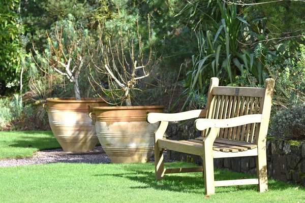 Eine Hölzerne Gartenbank Neben Zwei Terrakottaurnen Rosemoor Einem Englischen Landgarten lizenzfreie Stockfotos