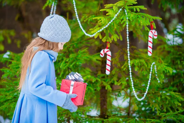 Little beautiful girl with christmas box gift in winter day outdoors. New Year coming soon — Stock Photo, Image