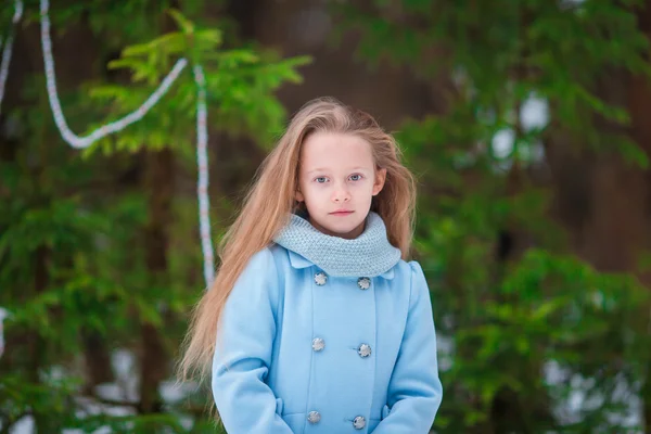 Portrait de petite adorable fille en manteau bleu et mitaines debout près du sapin de Noël décoré sur givré jour d'hiver en plein air — Photo