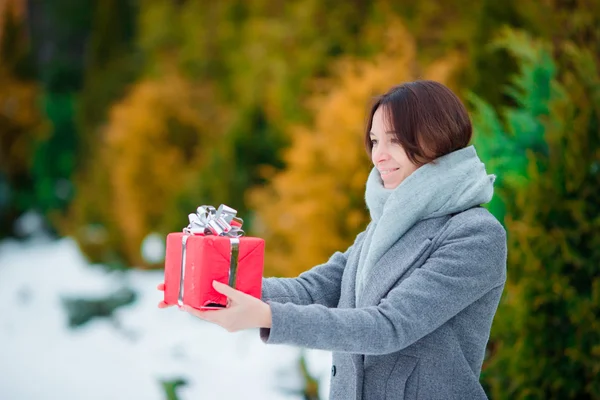 Glad tjej med röd jul ruta gåva i vinter dag utomhus — Stockfoto