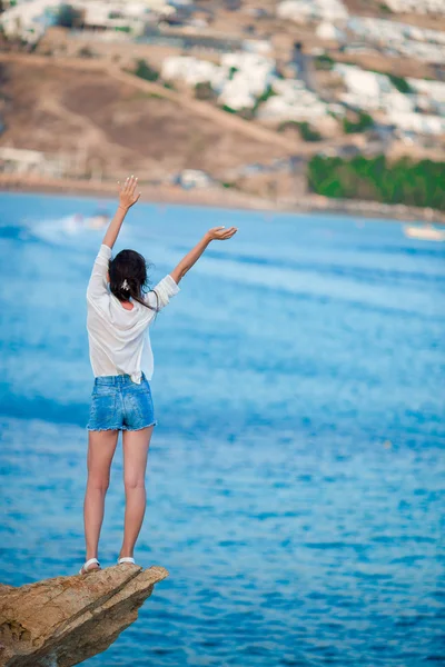 Giovane ragazza felice sulla spiaggia con splendida vista sul vecchio piccolo villaggio di Mykonos, greco — Foto Stock