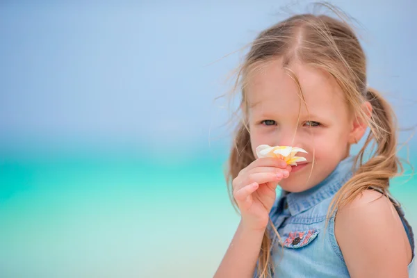 Retrato de niña adorable con flores frangipani en vacaciones de verano en la playa —  Fotos de Stock