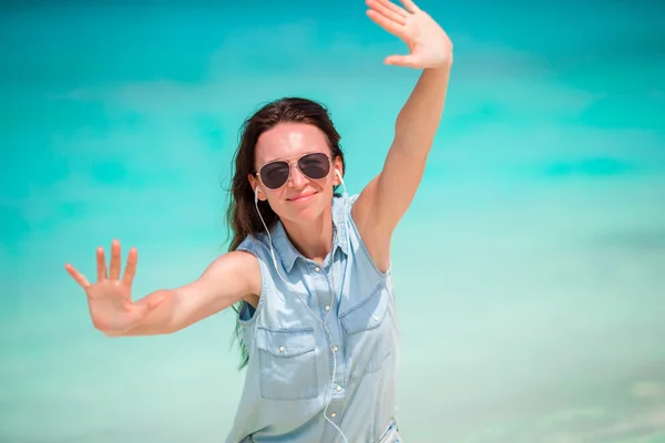 Joven hermosa mujer durante las vacaciones en la playa tropical. Disfruta de vacaciones de verano sola en la playa con flores de frangipani en el pelo — Foto de Stock