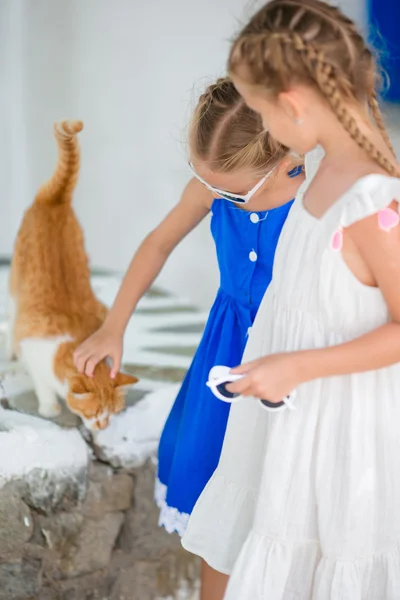 Close-up de meninas adoráveis Little acariciando um gato vermelho na aldeia grega, Mykonos, Grécia, Europa — Fotografia de Stock