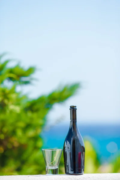 Glass and bottle of tasty red wine on balcony in greek island with view of sea — Stock Photo, Image