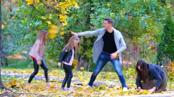 Jeune famille de quatre personnes jetant des feuilles un jour d'automne à l'extérieur 