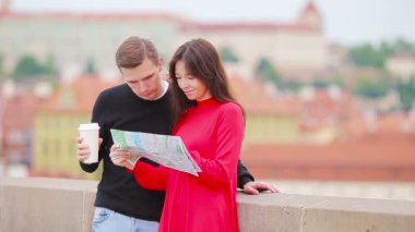 Avrupa 'da tatil yapan genç turist çift mutlu bir şekilde gülümsüyor. Şehir haritası olan beyaz bir aile cazibe arıyor.