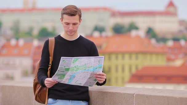 Man turist med en stadskarta och ryggsäck i Europa. Vit pojke tittar med karta över europeisk stad på jakt efter attraktioner. — Stockvideo