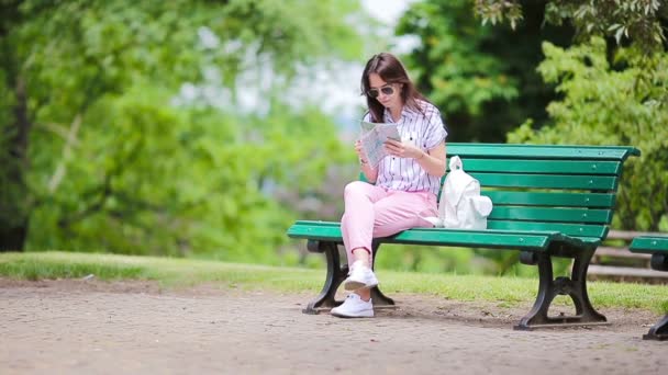 Glückliche junge Frau mit einem Stadtplan in Europa. Touristin mit Karte im Park im Freien in den Ferien — Stockvideo