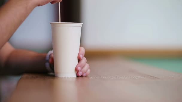 Gros plan des mains masculines mélanger le sucre dans un verre avec café dans le café . — Video