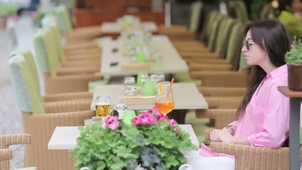 Portrét mladé krásné ženy sedící v kavárně venku a popíjející chutný koktejl. Šťastný turista vychutnat evropské svátky na openair restarteta — Stock video