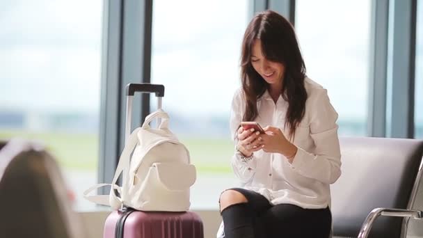 Pasajero de aerolínea en un salón del aeropuerto esperando aviones de vuelo. Caucásico mujer talkbe teléfono celular en la sala de espera — Vídeo de stock