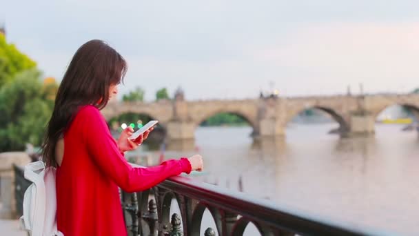 Νεαρή καυκάσια γυναίκα που χρησιμοποιεί το smartphone της εξωτερικό φόντο διάσημη γέφυρα. — Αρχείο Βίντεο
