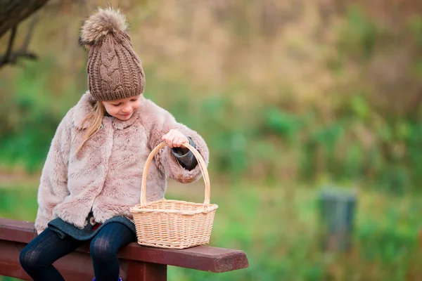 Adorabile bambina con un cesto in autunno giorno all'aperto — Foto Stock