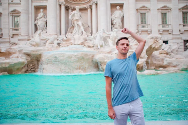 Jongeman toerist die munten gooit bij Trevi Fontein, Rome, Italië voor geluk. Blanke man doet een wens om terug te komen. — Stockfoto