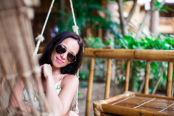 Krásná bruneta žena relaxaci v houpací síti na exotické luxusní hotel — Stock fotografie