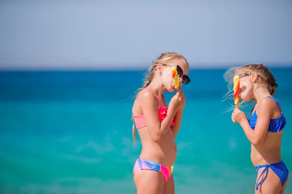 Šťastné holčičky jedí zmrzlinu během dovolené na pláži. Lidé, děti, přátelé a pojetí přátelství — Stock fotografie