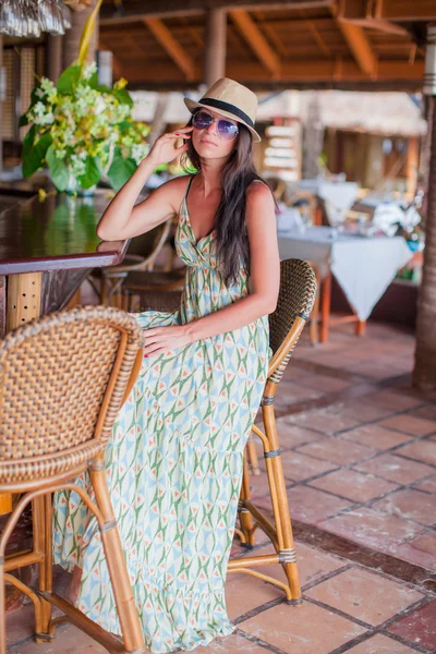 Schöne brünette Frau in langem Kleid und Hut entspannen in Strandrestaurantant — Stockfoto