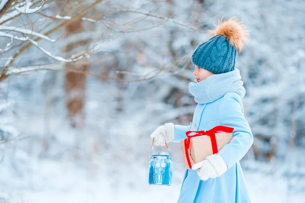 Adorable petite fille portant un manteau chaud à l'extérieur le jour de Noël tenant cadeau et lampe de poche — Photo