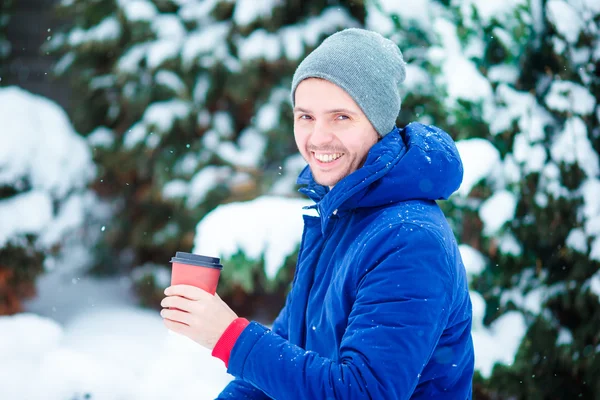 Young caucasian man drinking hot coffee in frozen winter day outdoors