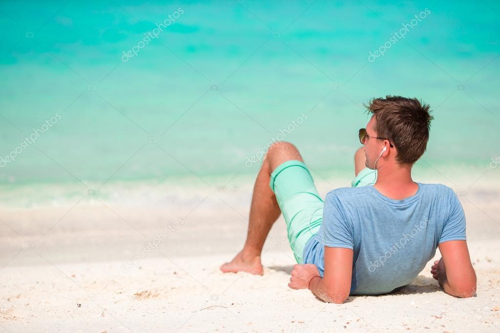 Happy young man enjoying time on white sandy beach