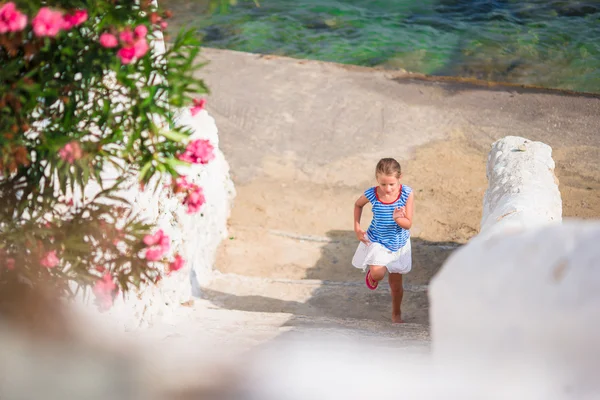 Adorable fille qui s'amuse à l'extérieur. Enfant dans la rue d'un village traditionnel grec typique avec des murs blancs et des portes colorées sur l'île de Mykonos, en Grèce — Photo