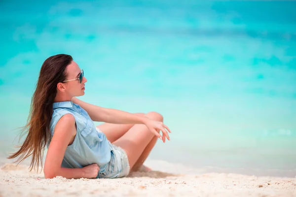Junge schöne Frau während eines tropischen Strandurlaubs. Sommerurlaub allein am Strand genießen, Frangipani-Blumen im Haar — Stockfoto