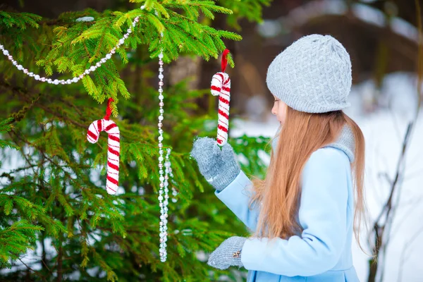 Portrait de petite adorable fille en manteau bleu et mitaines debout près du sapin de Noël décoré sur givré jour d'hiver en plein air — Photo