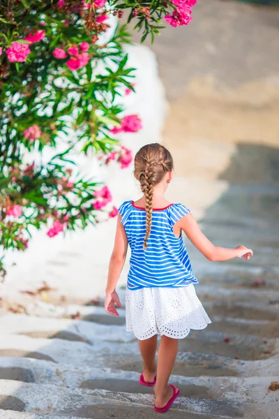 Ragazza adorabile divertirsi all'aperto. Ragazzo in strada del tipico villaggio greco tradizionale con pareti bianche e porte colorate sull'isola di Mykonos, in Grecia — Foto Stock