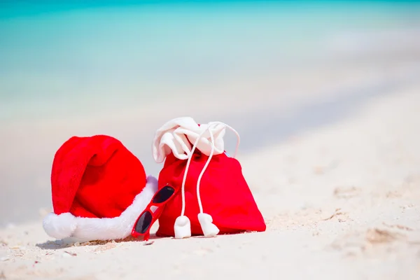 Christmas accessories on white beach. Xmas travel vacation and travel cuprise concept. Beach accessories with Santa Hat on white tropical beach — Stock Photo, Image