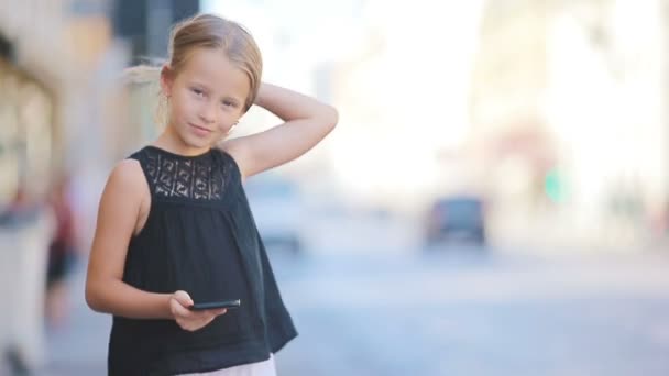 Красивая маленькая девочка со смартфоном на открытом воздухе в европейском городе, Рим, Италия — стоковое видео