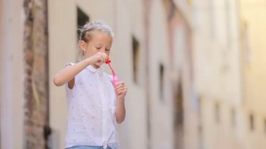 Avrupa 'nın dar sokaklarında sabun köpüğü üfleyen küçük bir kız. Kafkas çocuk portresi Roma 'da yaz tatilinin keyfini çıkarın