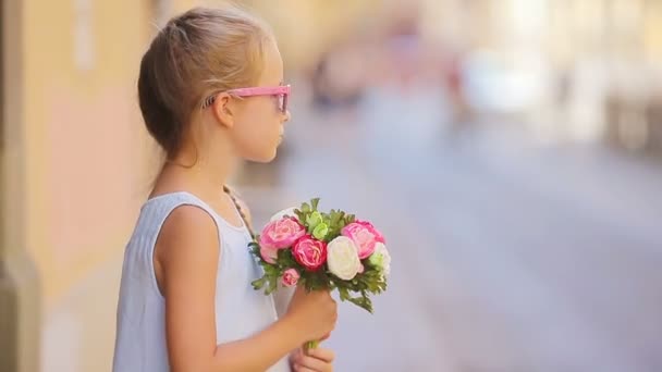 Adorable petite fille avec bouquet de fleurs marchant dans la ville européenne en plein air — Video