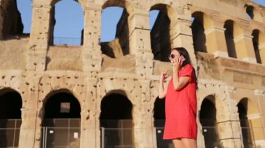 İtalya, Roma 'da kolezyum önünde akıllı telefondan konuşan genç bir kadın. Kız İtalya 'da tatilde.