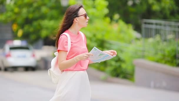 Haritası olan mutlu genç bir kadın Avrupa 'da şehir caddesinde yürüyor ve başka bir beyaz kıza yardım istiyor. — Stok video