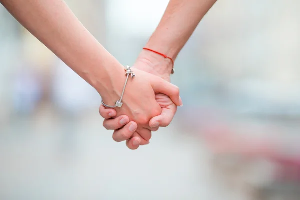 Close up of girl and boy holding each other hands in city outdoor — Stock Photo, Image