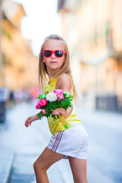 Entzückendes kleines Mädchen mit Blumenstrauß zu Fuß in der europäischen Stadt — Stockfoto