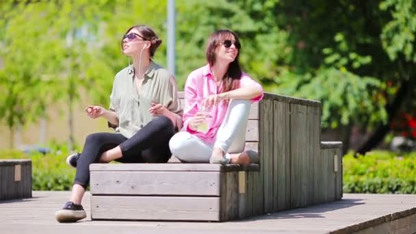 Meninas bonitas ouvir música por smartphone em férias de verão. Jovens turistas atraentes com telefone celular ao ar livre desfrutando de férias . — Vídeo de Stock