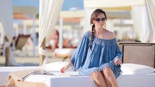 Mujer joven durante las vacaciones en la playa tropical. Chica de moda en tumbonas blancas en weekeend playa europea — Vídeo de stock
