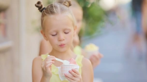 夏に屋外でアイスクリームを食べる愛らしい女の子。ローマのゲラテリア近くで本物のイタリアのジェラートを楽しむかわいい子供たち — ストック動画