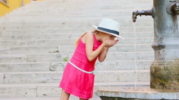 A kis imádnivaló lány vizet iszik a csapból kint a forró nyári napon Rómában, Olaszországban. — Stock videók
