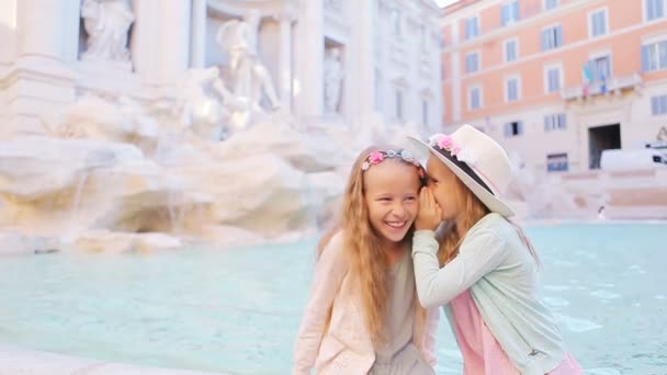 Adorable little girls whispering sitting on the edge of Fountain of Trevi in Rome. Happy kids enjoy their european vacation in Italy — Stock Video