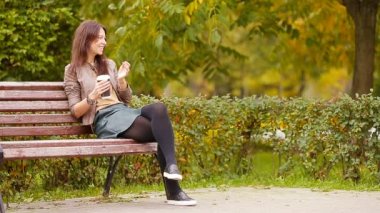 Sonbahar konsepti: Sonbahar parkında sonbahar yaprakları altında kahve içen güzel bir kadın.